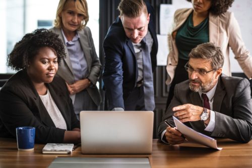 diverse group of people looking at a laptop