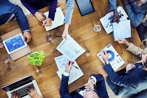 overhead view of people at a meeting passing papers