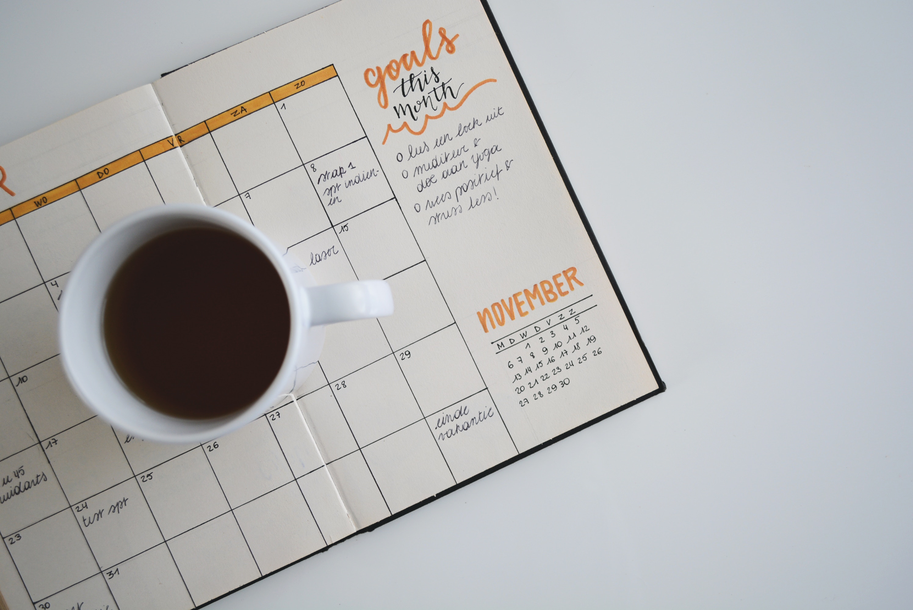 image of day planner with cup of coffee next to it